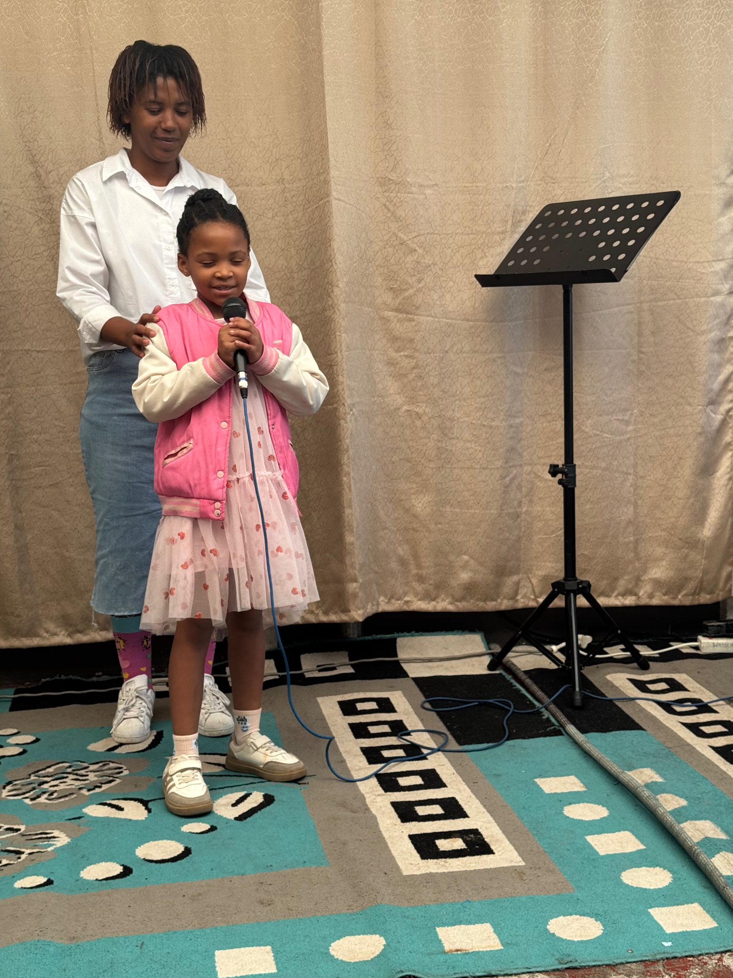 A little girl praying on the microphone with her teacher
