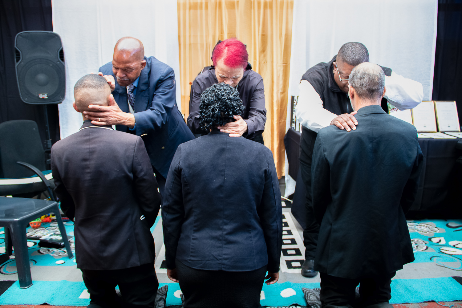 Church leaders laying hands in prayer during an ordination service