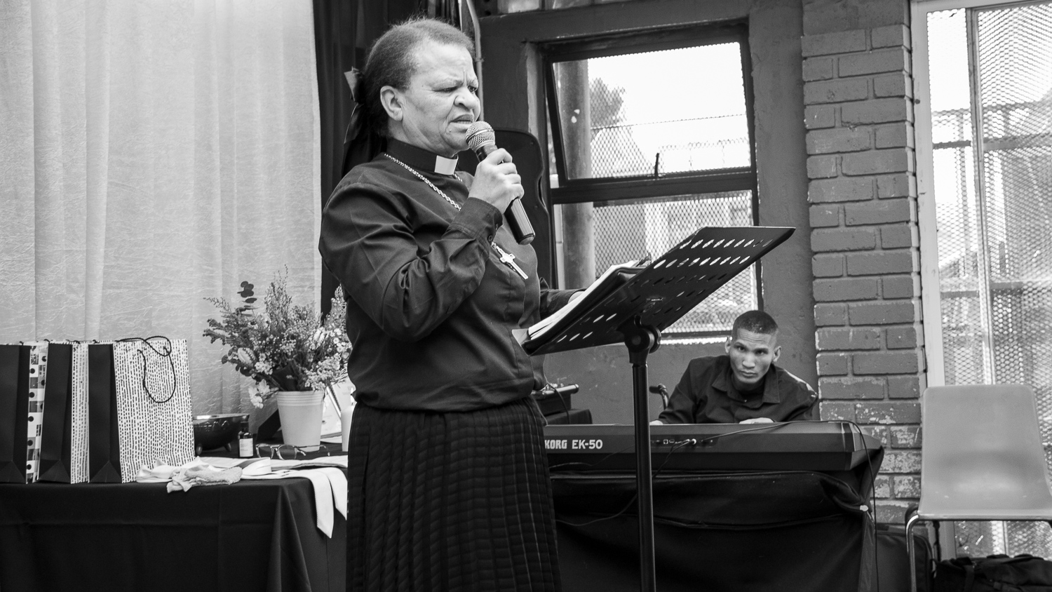 Pastor L. van Rooyen ministering while a musician plays keyboard